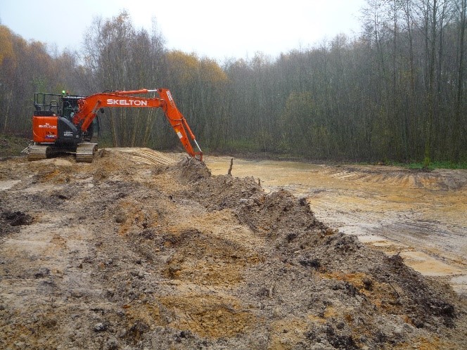 Oragnge digger removes soil to create a pond