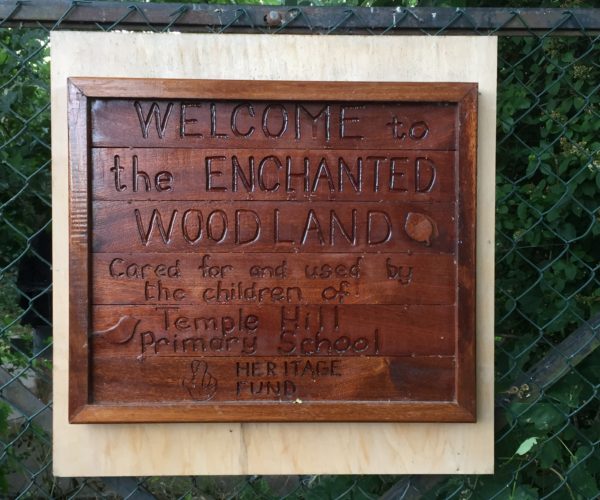 Small wooden sign saying welcome to the Enchanted Woodland