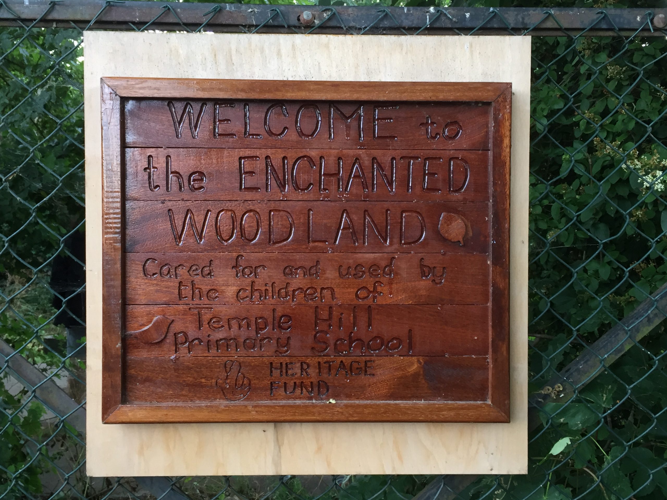 Small wooden sign saying welcome to the Enchanted Woodland