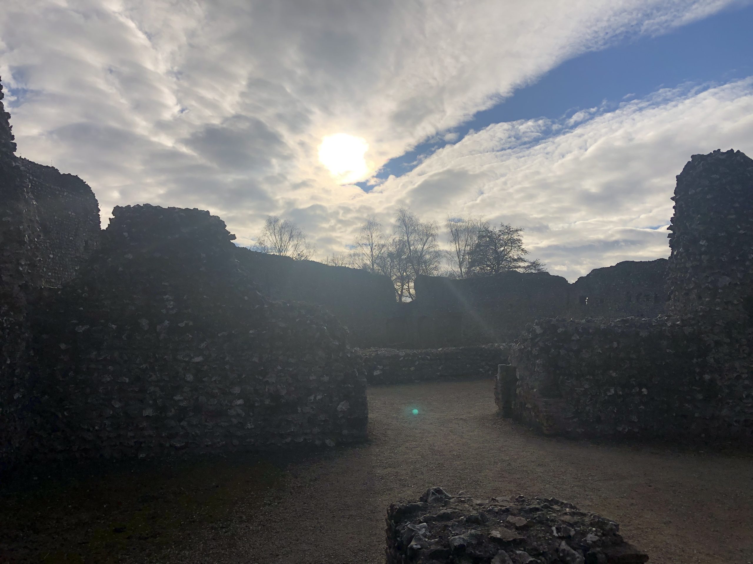 Sun breaking through clouds over old ruin