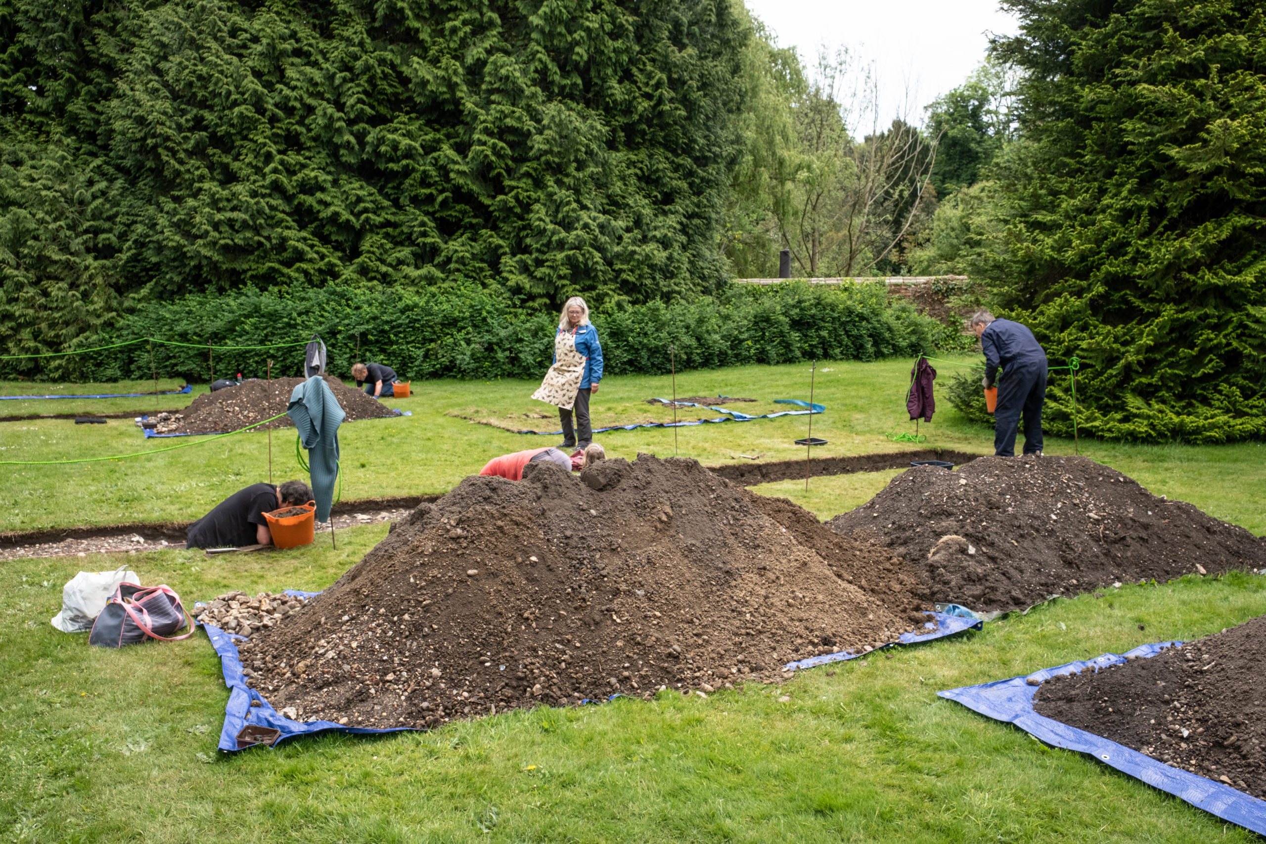 Two people digging in trench in ground with mounds of earth in front