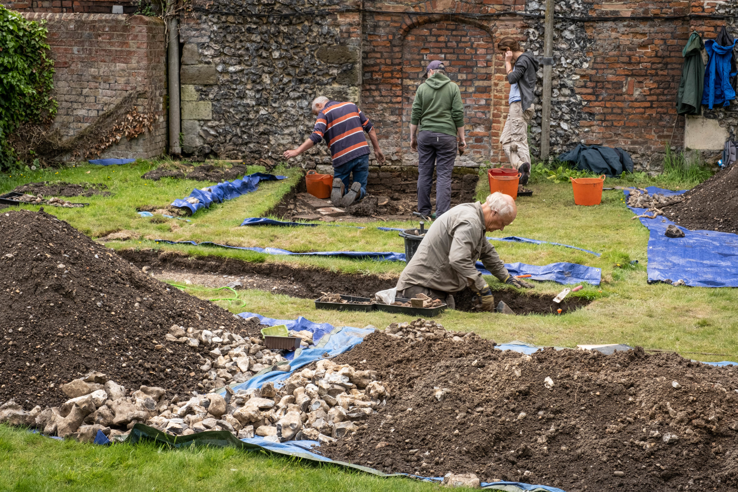 Four people in archaeological trench in ground