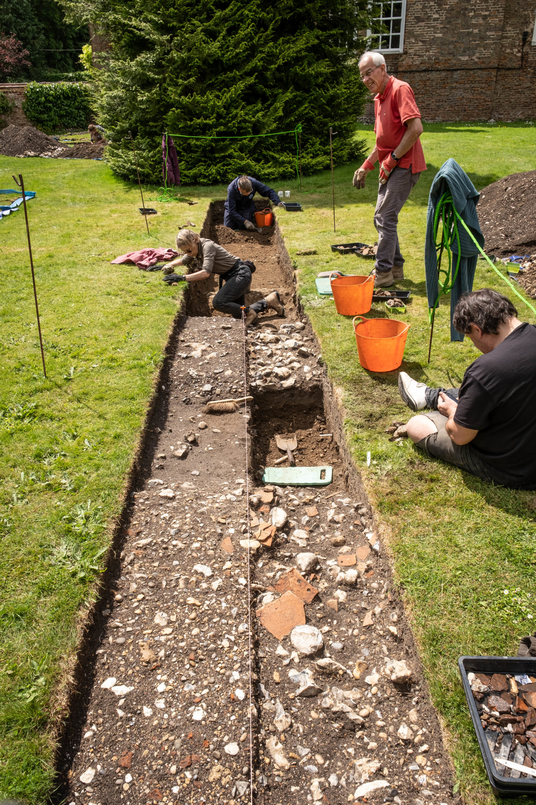 Four people digging in long rectangular trench at Lullingstone Castle