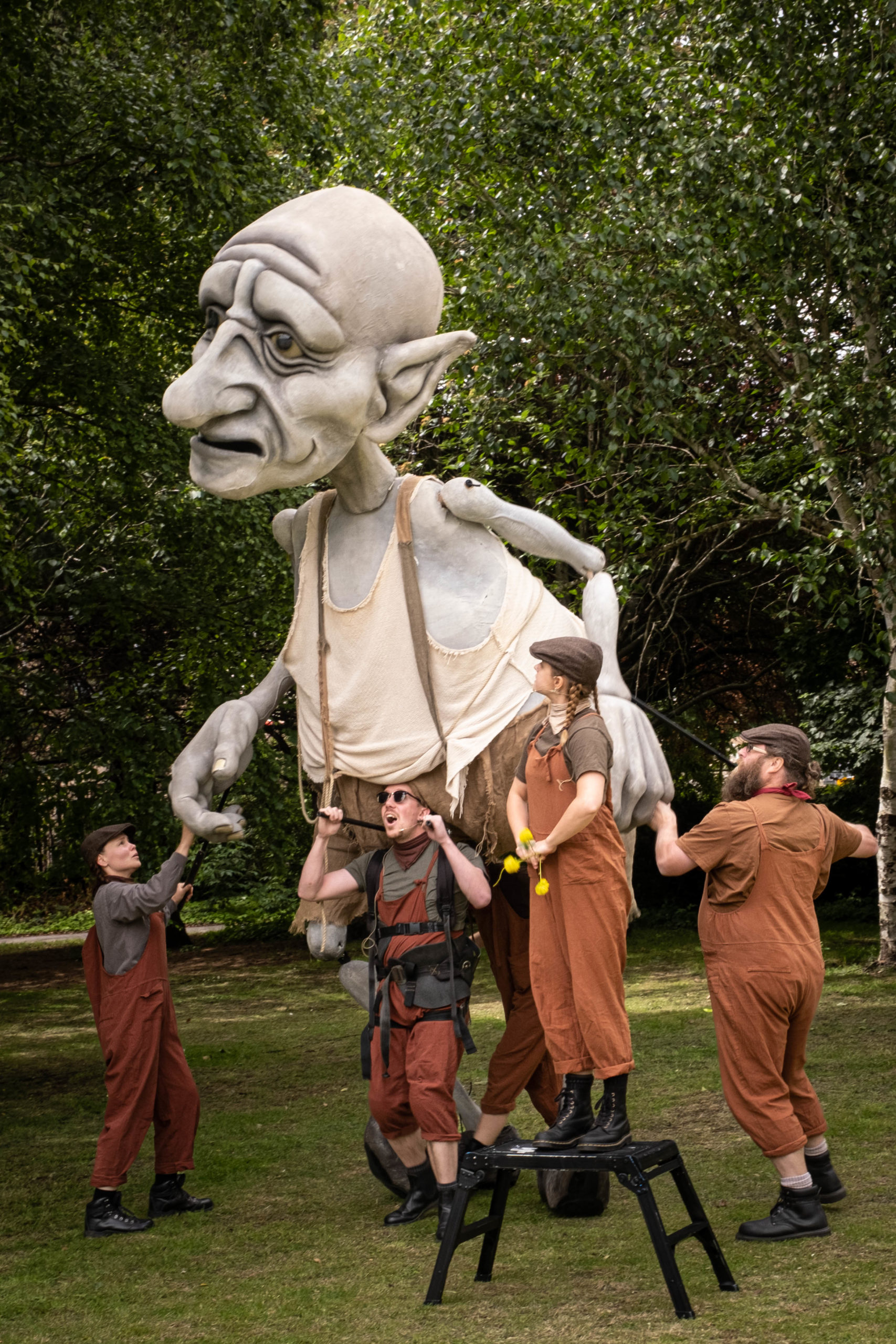 Large giant puppet being moved by four people in a field
