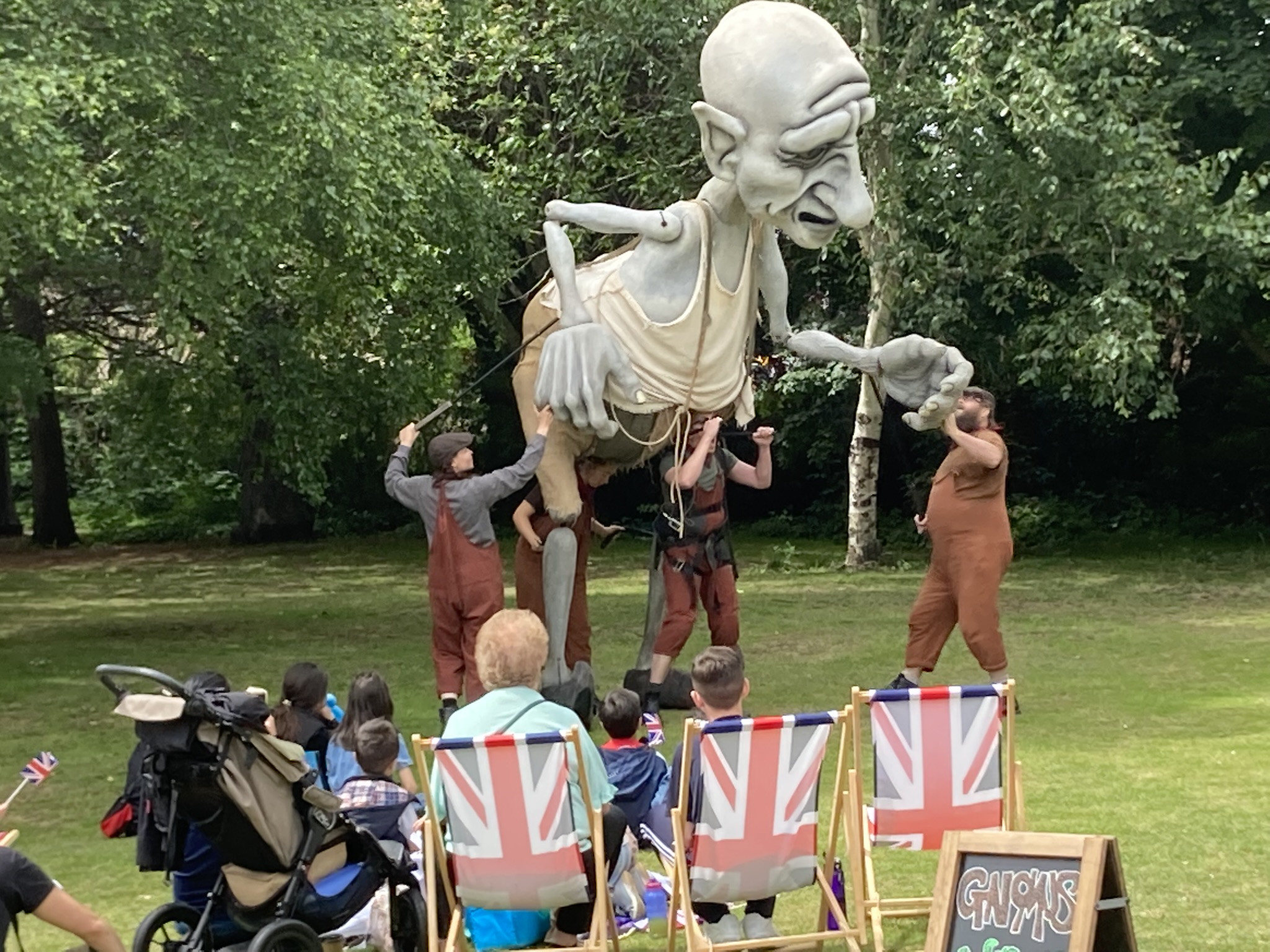 Large puppet being moved by three people with crowd watching