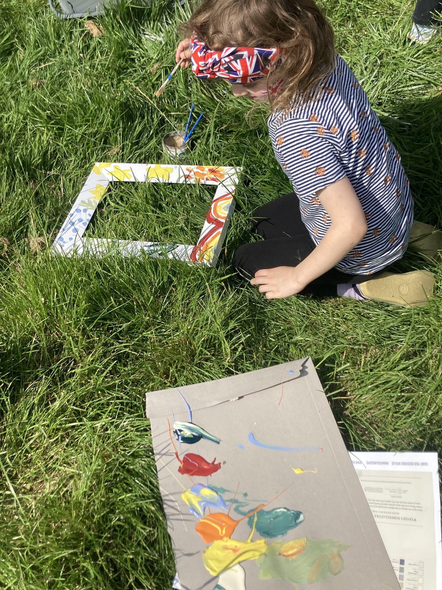 Girl painting frame on grass